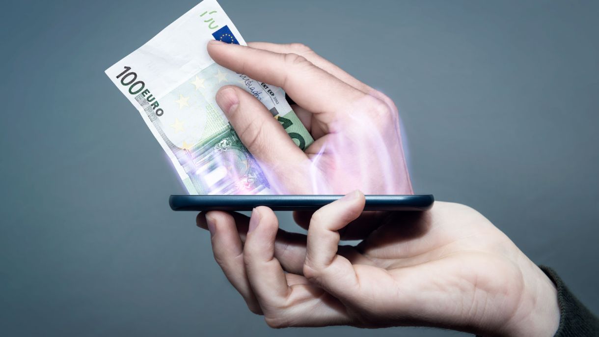 Eine Hand hält ein Handy aus dem eine Hand mit Geldscheinen kommt.