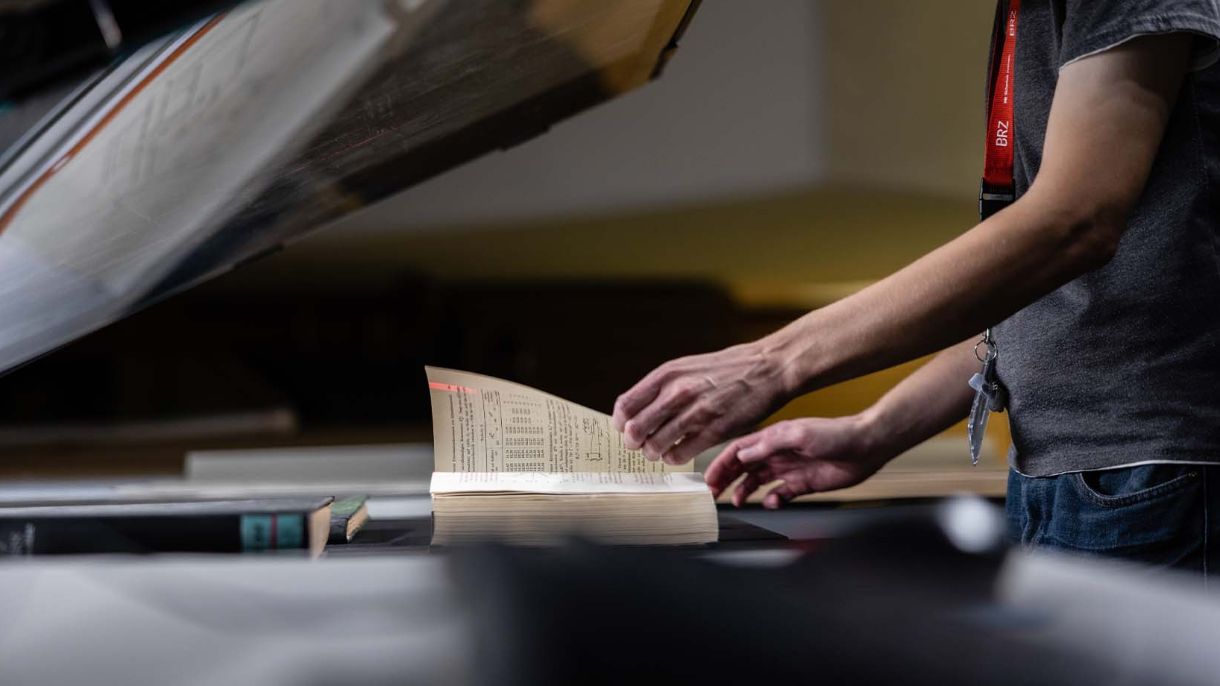 Mitarbeiter aus dem BRZ-Scanzentrum in Erdberg scannt ein Buch. 