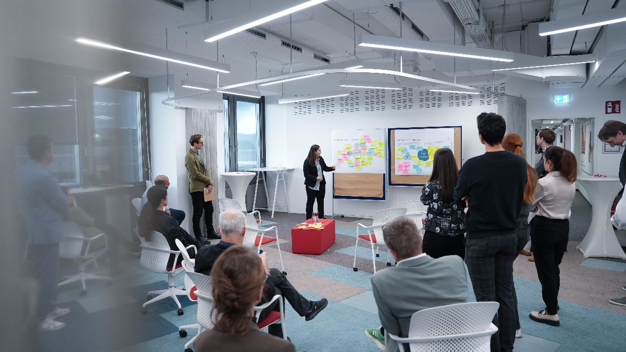 Eine Gruppe am Menschen stehend und sitzend im Raum verteilt