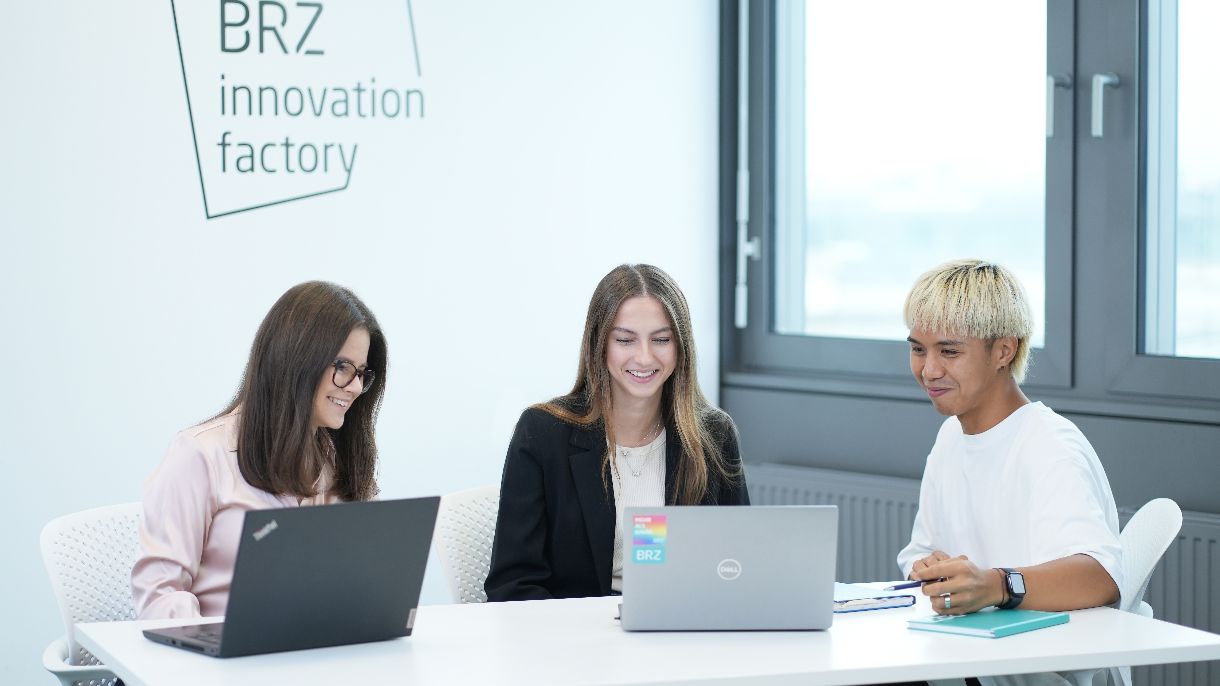 Zwei Kolleginnen und ein Kollege arbeiten am Laptop gemeinsam