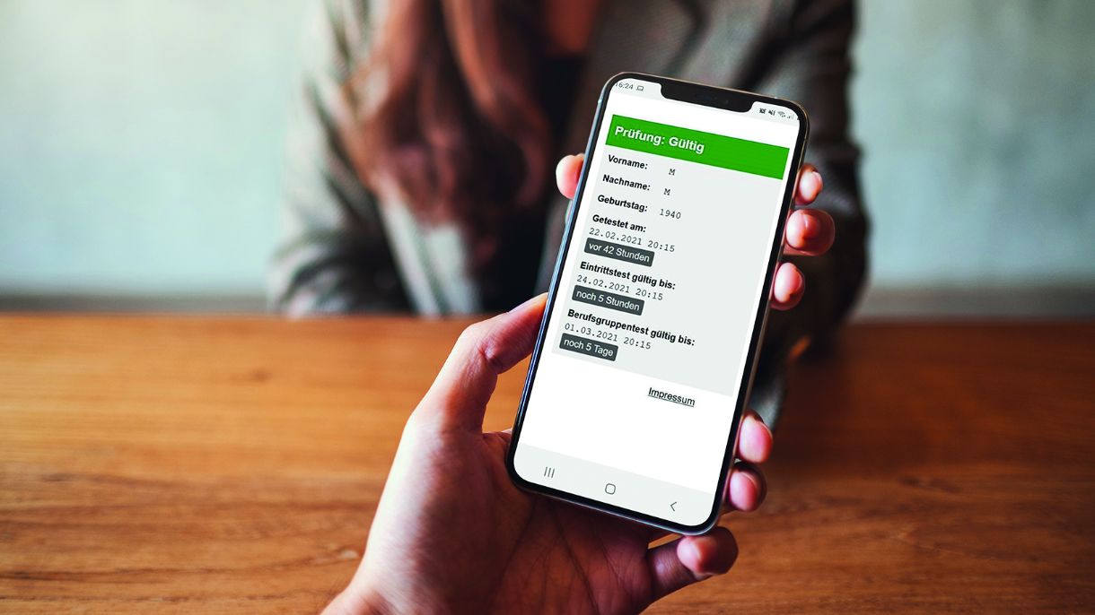 Eine Person hält ein Smartphone. Am Display ist ein Eintrittstest zu sehen. 