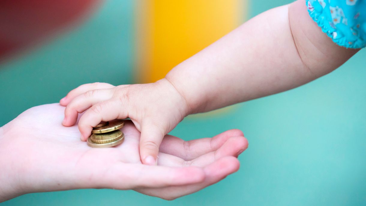 Babyhand nimmt Münzen aus Erwachsenenhand