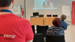 Teilnehmer des govcamp sehen eine Videobotschaft von Staatssekretär Florian Tursky