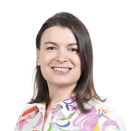 Frau mit dunklem Haar und bunter Bluse lächelt