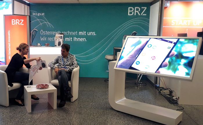 BRZ Ausstellungsstand bei We are Developers, eine Frau und ein Mann sitzen in Lounge-Möbeln