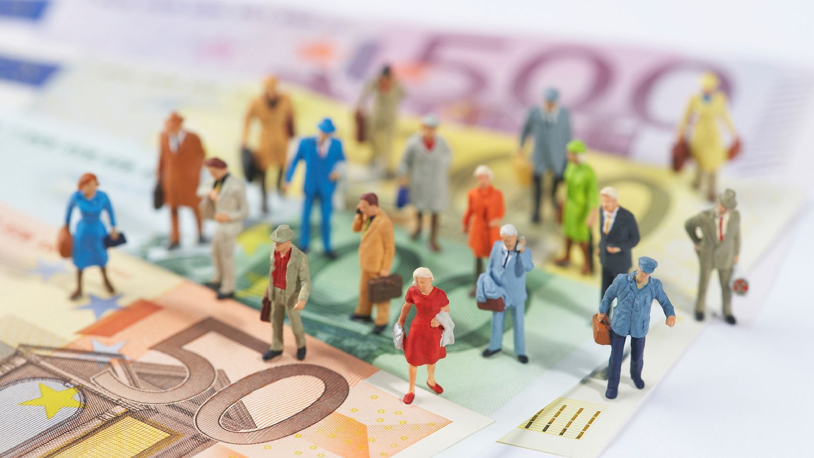 little plastic figures of people are standing on Euro bills