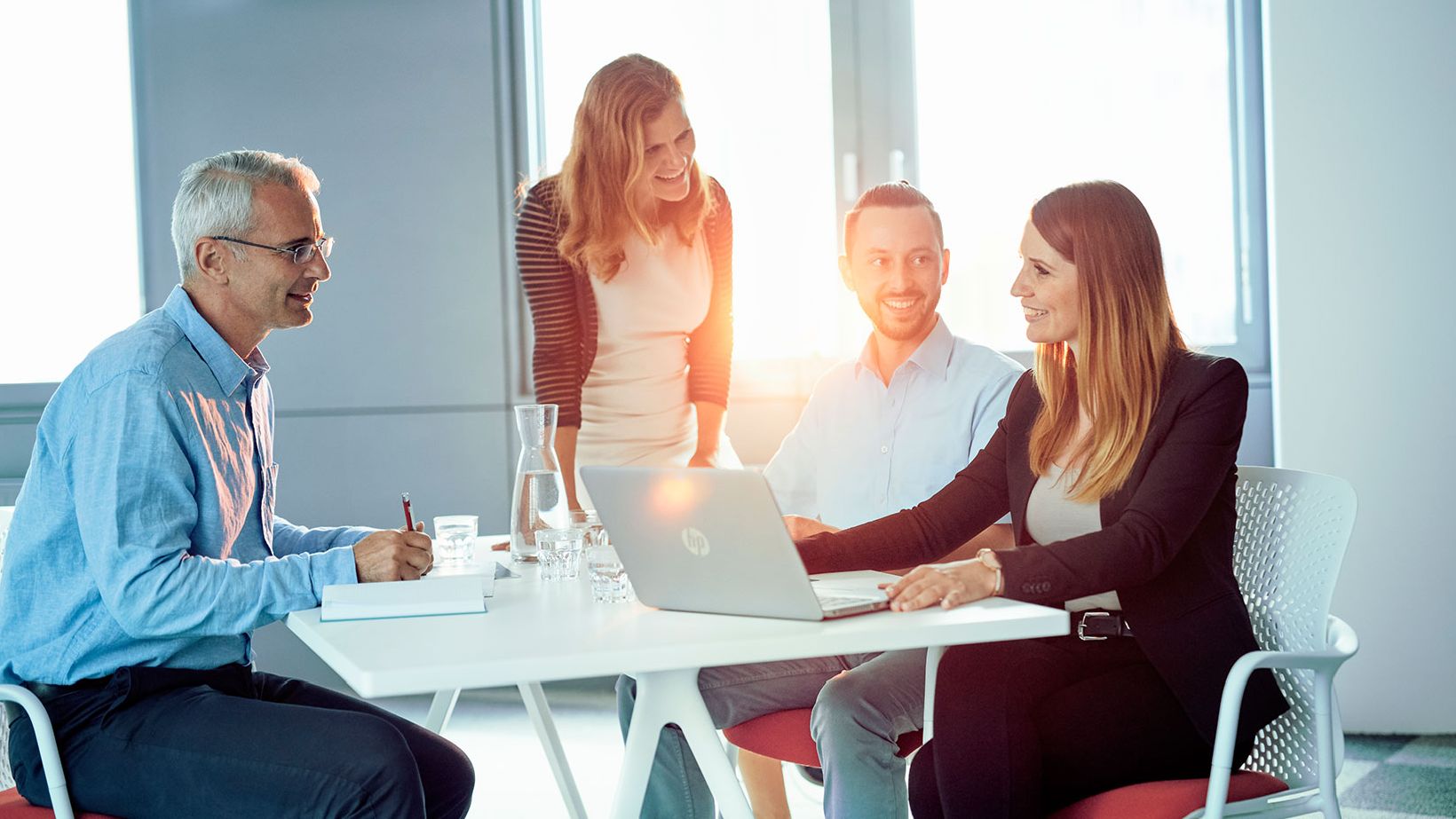 Grupppe von BRZ-Mitarbeiterinnen und Mitarbeitern bei der Arbeit in der Innovation Factory. Oranges Licht durchdringt atmosphärisch die lockere, aber produktive Arbeit.