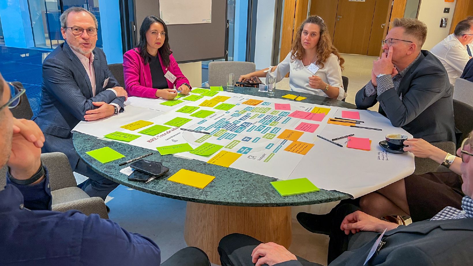 Menschen sitzen an einem Tisch mit Postit-Notes