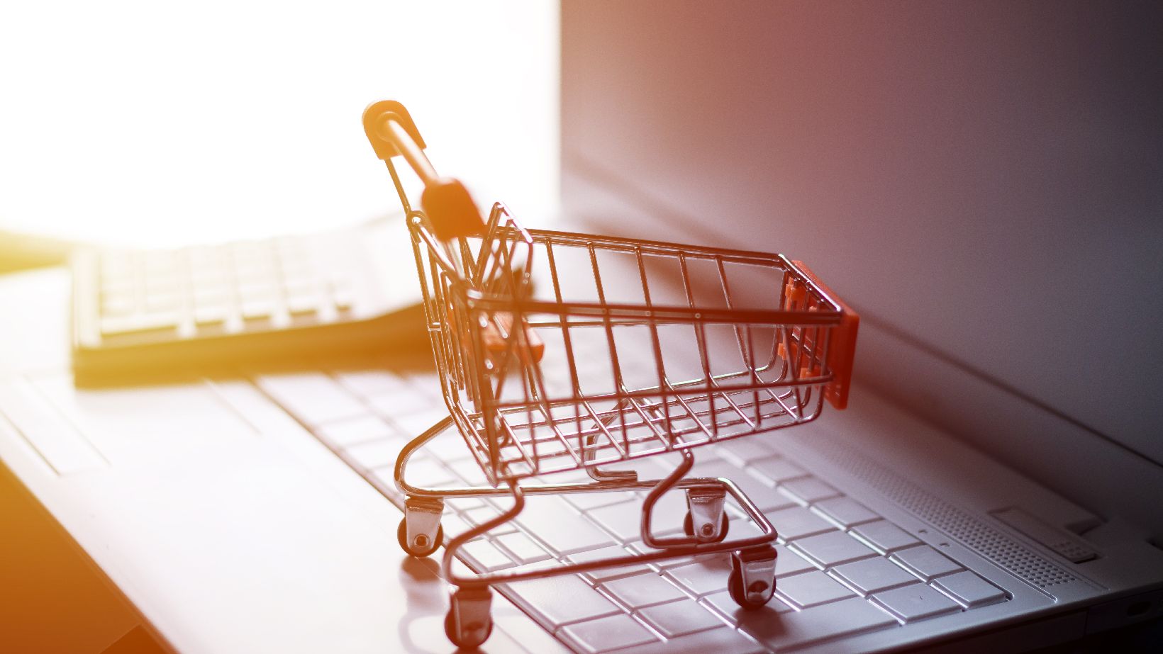 Beschaffungsplattform, @iStock.com/Mahmud013 kleiner Einkaufwagen und Taschenrechner stehen auf einem Laptop