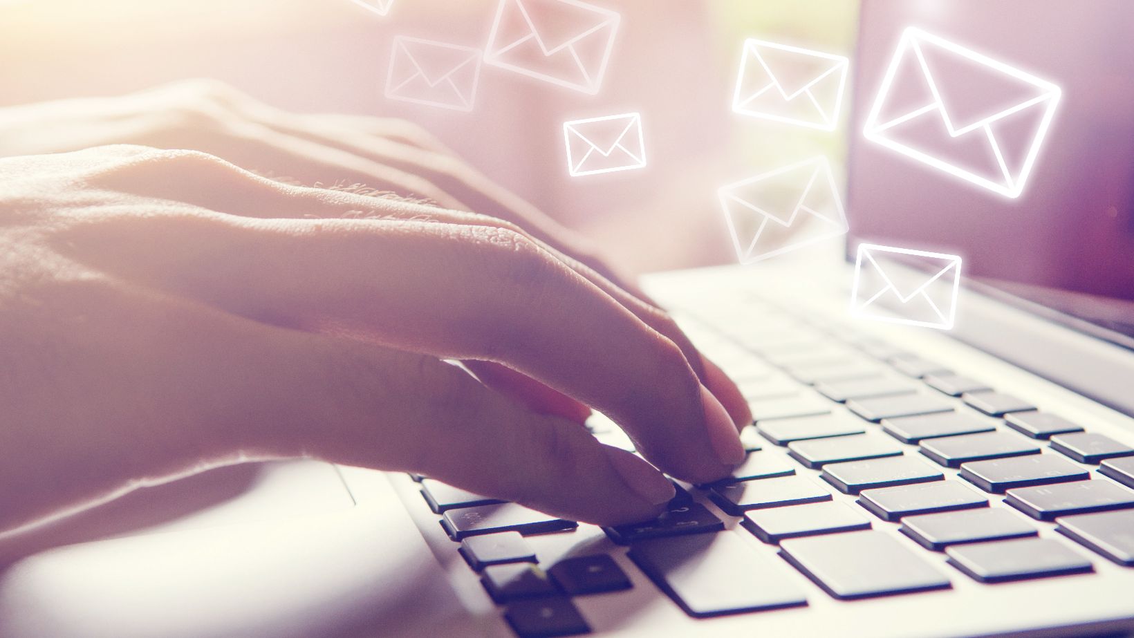 Mailing Services, @iStock.com/oatawa Hände Tippen auf einem Laptop Keyboard. E-Mail Icons fliegen aus dem Laptop
