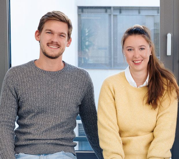 Eine Kollegin und ein Kollege lächeln in die Kamera
